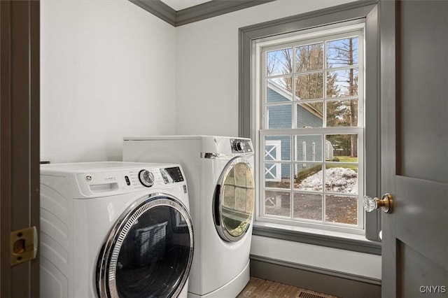 laundry room featuring washing machine and dryer, wood-type flooring, and ornamental molding