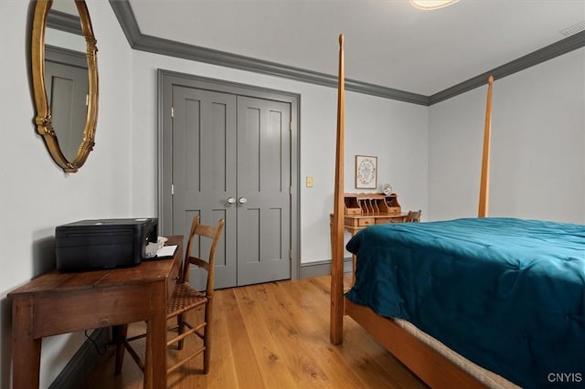 bedroom with light wood-type flooring, a closet, and crown molding