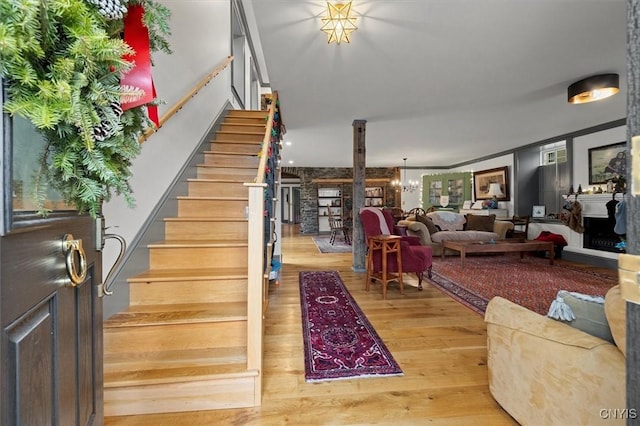 stairway featuring wood-type flooring, ornamental molding, and a chandelier