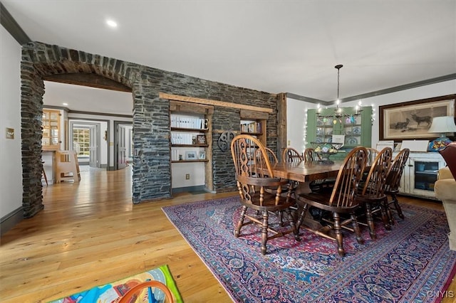 dining room with wood-type flooring, crown molding, and a chandelier