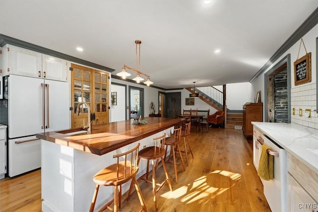 kitchen featuring decorative backsplash, light hardwood / wood-style flooring, hanging light fixtures, and white appliances