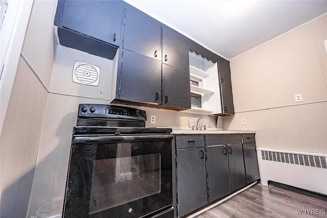 kitchen featuring radiator heating unit, dark hardwood / wood-style floors, black electric range oven, and sink