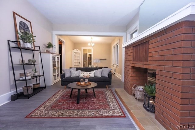 living room featuring a notable chandelier, wood-type flooring, and a brick fireplace