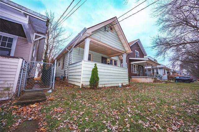 view of side of property with covered porch and a lawn