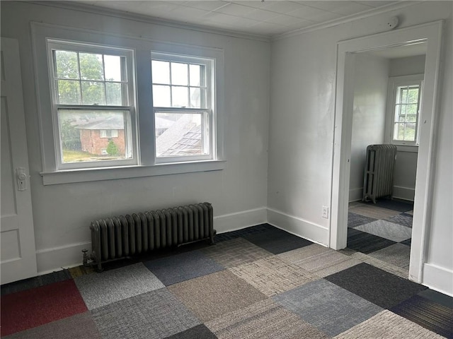 carpeted empty room with plenty of natural light, ornamental molding, and radiator