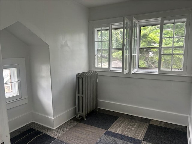 unfurnished room with dark colored carpet and radiator