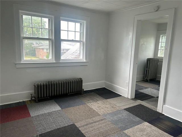 carpeted empty room featuring radiator heating unit and crown molding