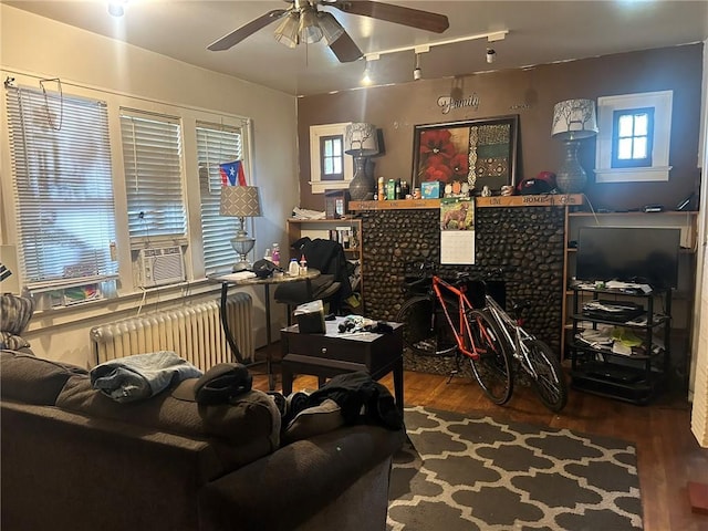 living room with dark hardwood / wood-style floors, ceiling fan, radiator heating unit, and cooling unit