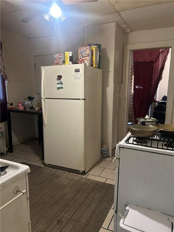 kitchen with light tile patterned floors, white appliances, and a paneled ceiling