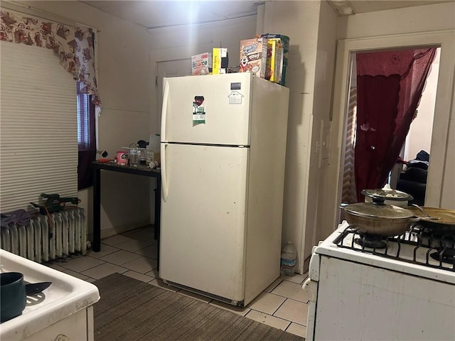 kitchen with light tile patterned floors, white appliances, and radiator