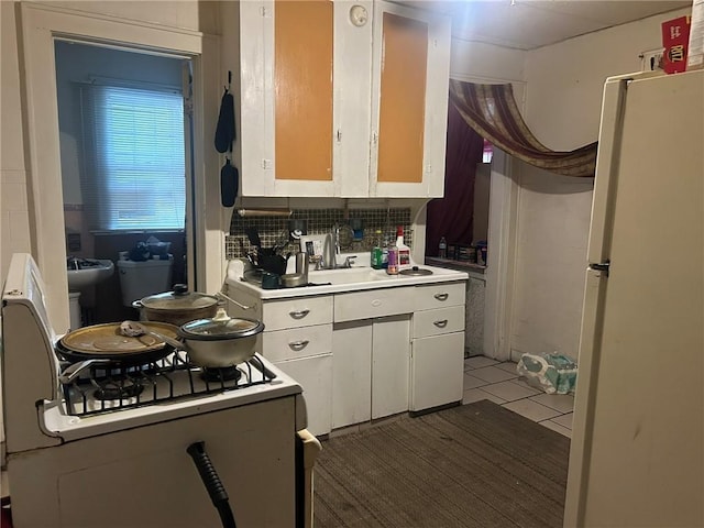 kitchen featuring backsplash, white cabinets, dark tile patterned flooring, white fridge, and range