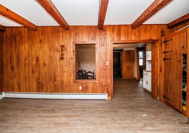 spare room with beam ceiling, wooden walls, a baseboard heating unit, and light wood-type flooring