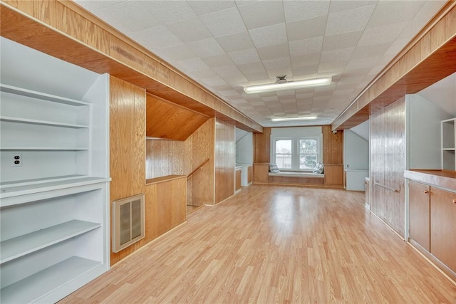 additional living space featuring wood walls, built in features, and light hardwood / wood-style floors