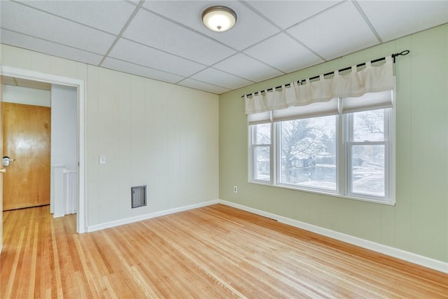 unfurnished room with hardwood / wood-style flooring and a drop ceiling