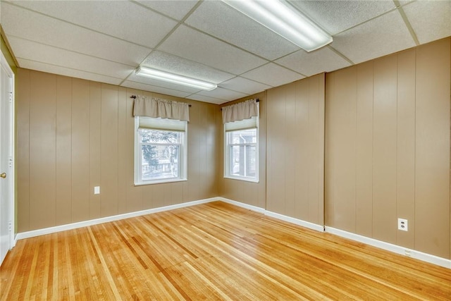 spare room with hardwood / wood-style flooring, a paneled ceiling, and wooden walls