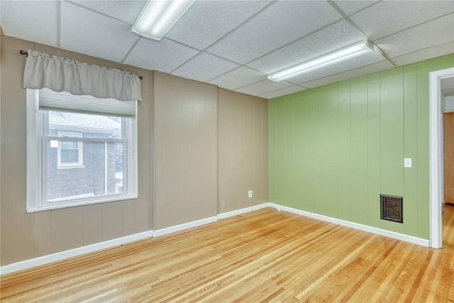 spare room with a paneled ceiling and hardwood / wood-style floors