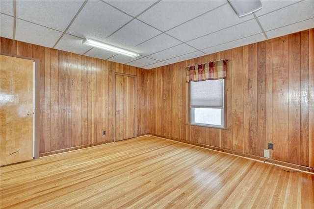 spare room with hardwood / wood-style floors, a paneled ceiling, and wooden walls