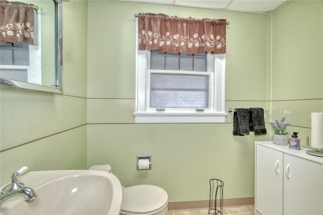 bathroom featuring toilet, tile patterned floors, a drop ceiling, and sink