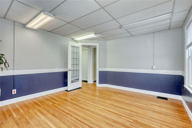 spare room featuring hardwood / wood-style floors and a drop ceiling