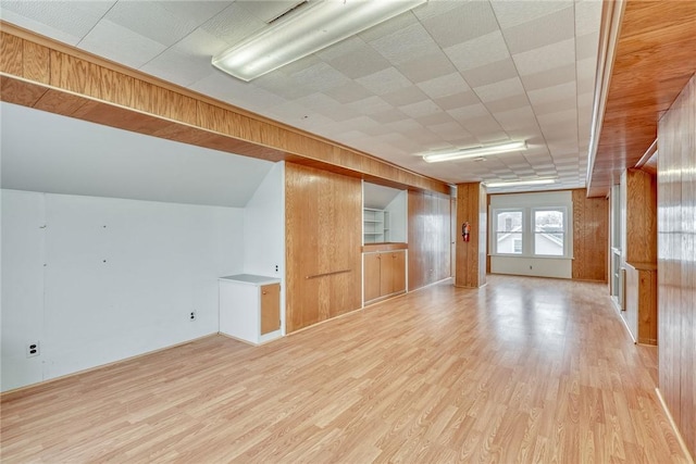 bonus room with light hardwood / wood-style flooring and wood walls