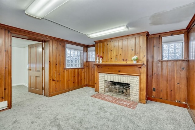 unfurnished living room featuring plenty of natural light, a fireplace, wooden walls, and light carpet