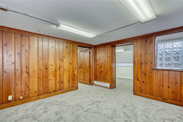 carpeted empty room with wooden walls and a baseboard heating unit