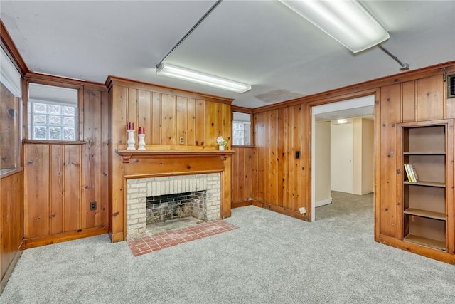 carpeted living room with wood walls, crown molding, and a brick fireplace