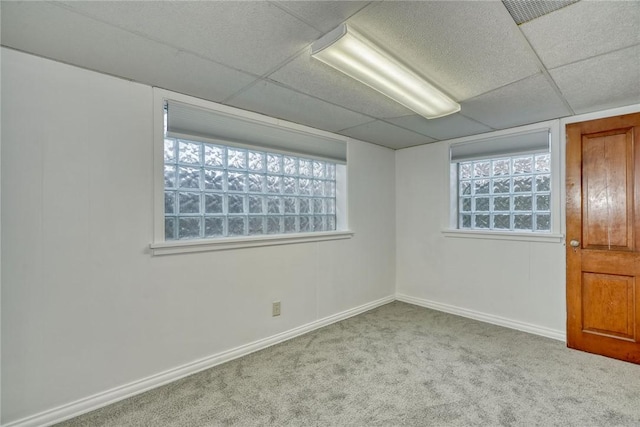 carpeted empty room featuring a paneled ceiling and a wealth of natural light