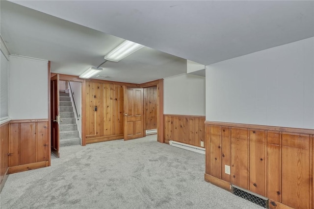 additional living space with light carpet, wooden walls, and a baseboard radiator