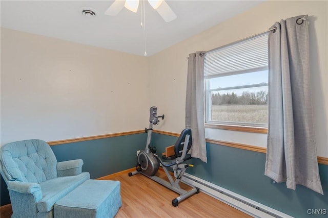 workout room with ceiling fan, baseboard heating, and wood-type flooring