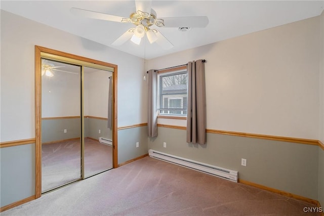 unfurnished bedroom with ceiling fan, carpet, a closet, and a baseboard heating unit