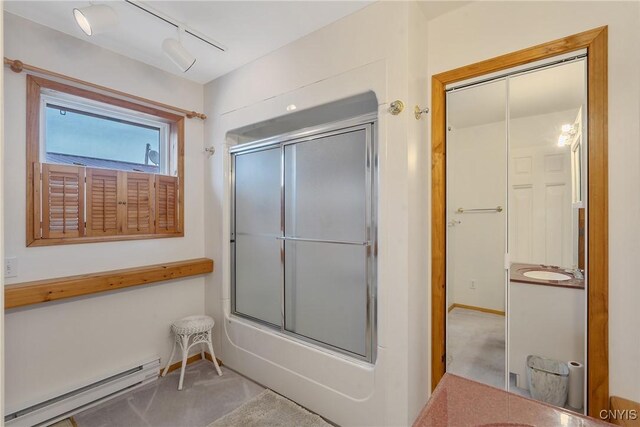 bathroom with vanity, track lighting, bath / shower combo with glass door, and a baseboard radiator