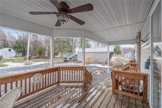 snow covered deck with ceiling fan and an outdoor structure