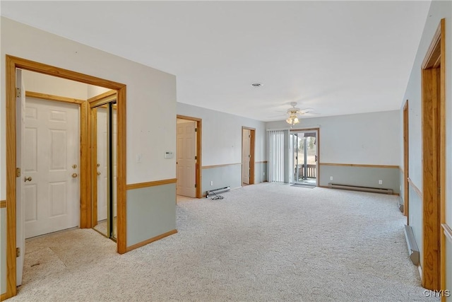 empty room with ceiling fan, light colored carpet, and a baseboard heating unit