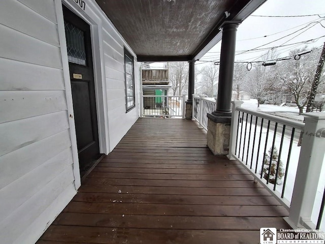 snow covered deck featuring covered porch