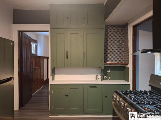 kitchen featuring stainless steel fridge, gas stove, wall chimney range hood, dark hardwood / wood-style floors, and green cabinets