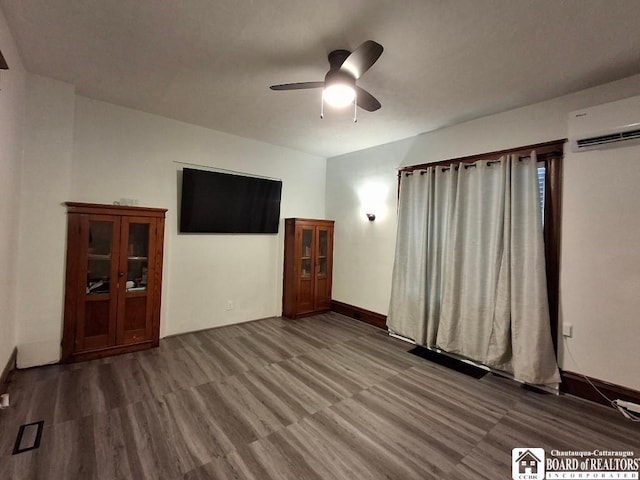 interior space featuring hardwood / wood-style flooring, a wall unit AC, and ceiling fan