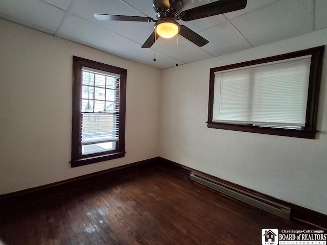 empty room featuring a drop ceiling, ceiling fan, and dark hardwood / wood-style flooring