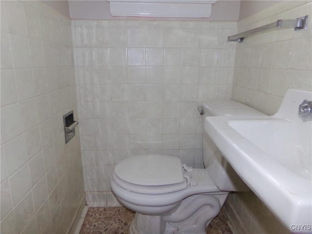 bathroom with tile patterned floors, toilet, tile walls, and washer / dryer