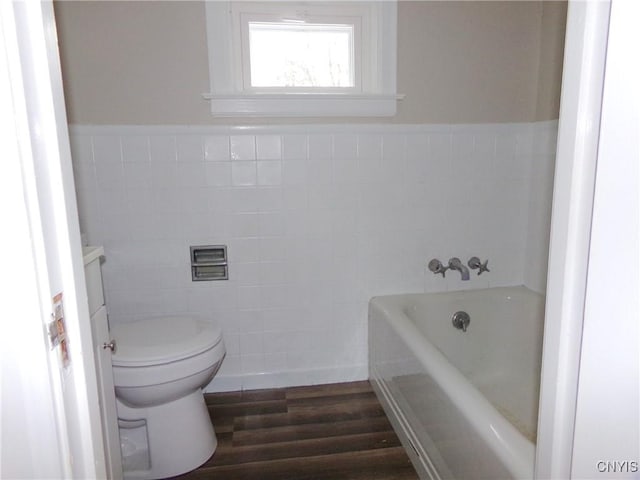 bathroom featuring a washtub, wood-type flooring, toilet, vanity, and tile walls