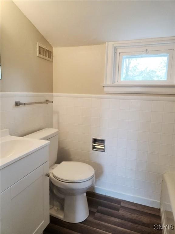 bathroom with hardwood / wood-style floors, vanity, tile walls, and vaulted ceiling