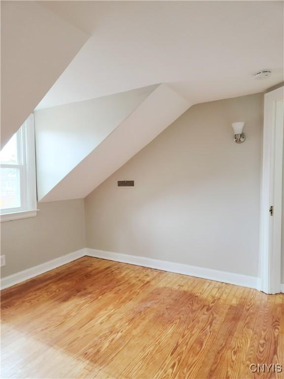 additional living space with wood-type flooring and vaulted ceiling