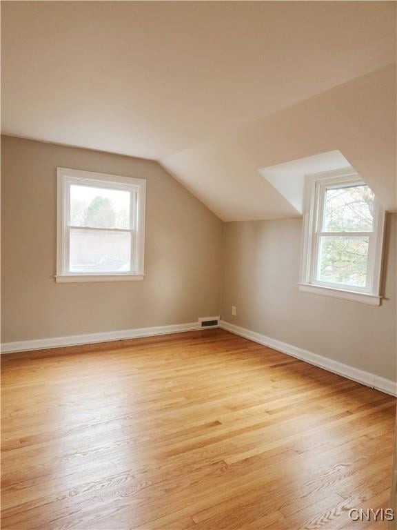 bonus room with a wealth of natural light, lofted ceiling, and light wood-type flooring