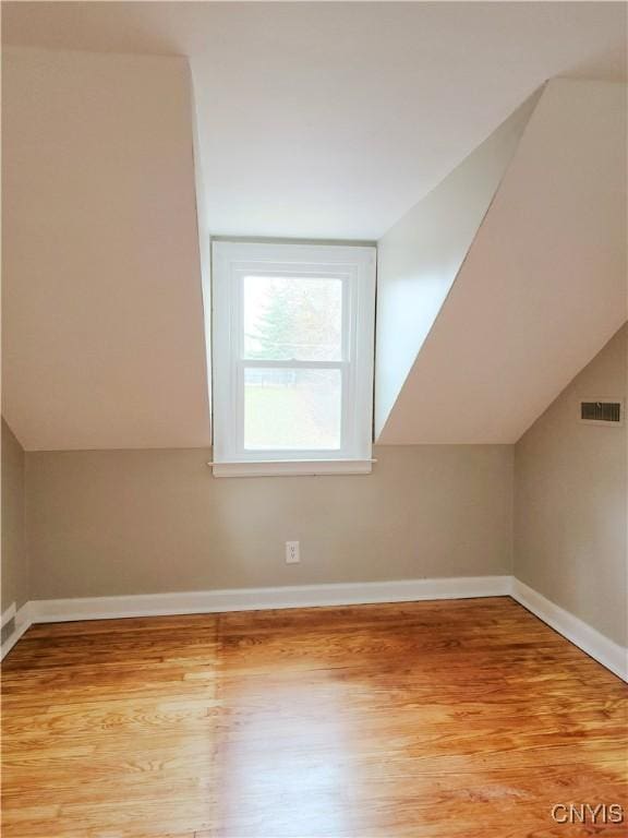 additional living space featuring light wood-type flooring and lofted ceiling