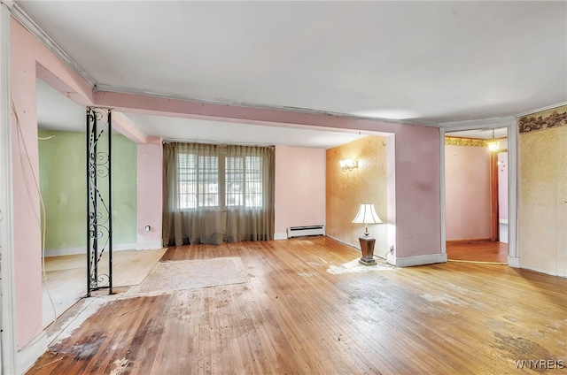 empty room featuring a baseboard heating unit and light hardwood / wood-style flooring