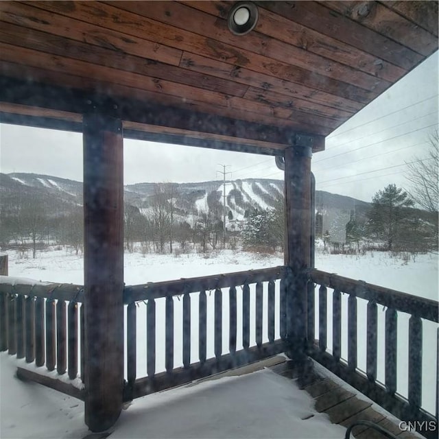 snow covered deck with a mountain view