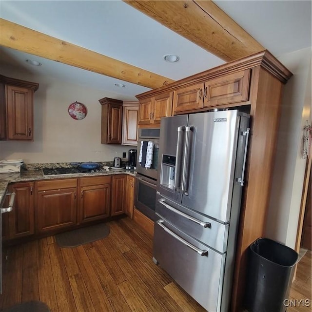 kitchen featuring beamed ceiling, dark hardwood / wood-style flooring, stainless steel appliances, and dark stone countertops