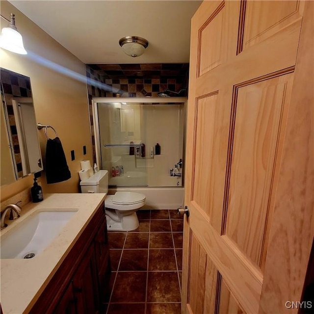 full bathroom featuring shower / bath combination with glass door, tile patterned flooring, vanity, and toilet