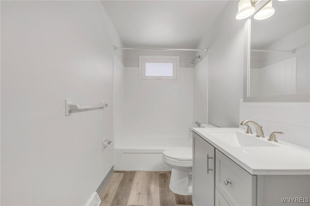 full bathroom with tiled shower / bath combo, wood-type flooring, toilet, decorative backsplash, and vanity