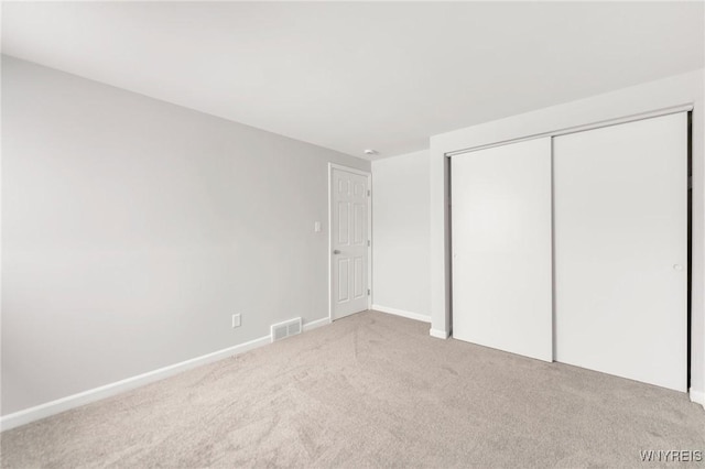 unfurnished bedroom with light colored carpet and a closet